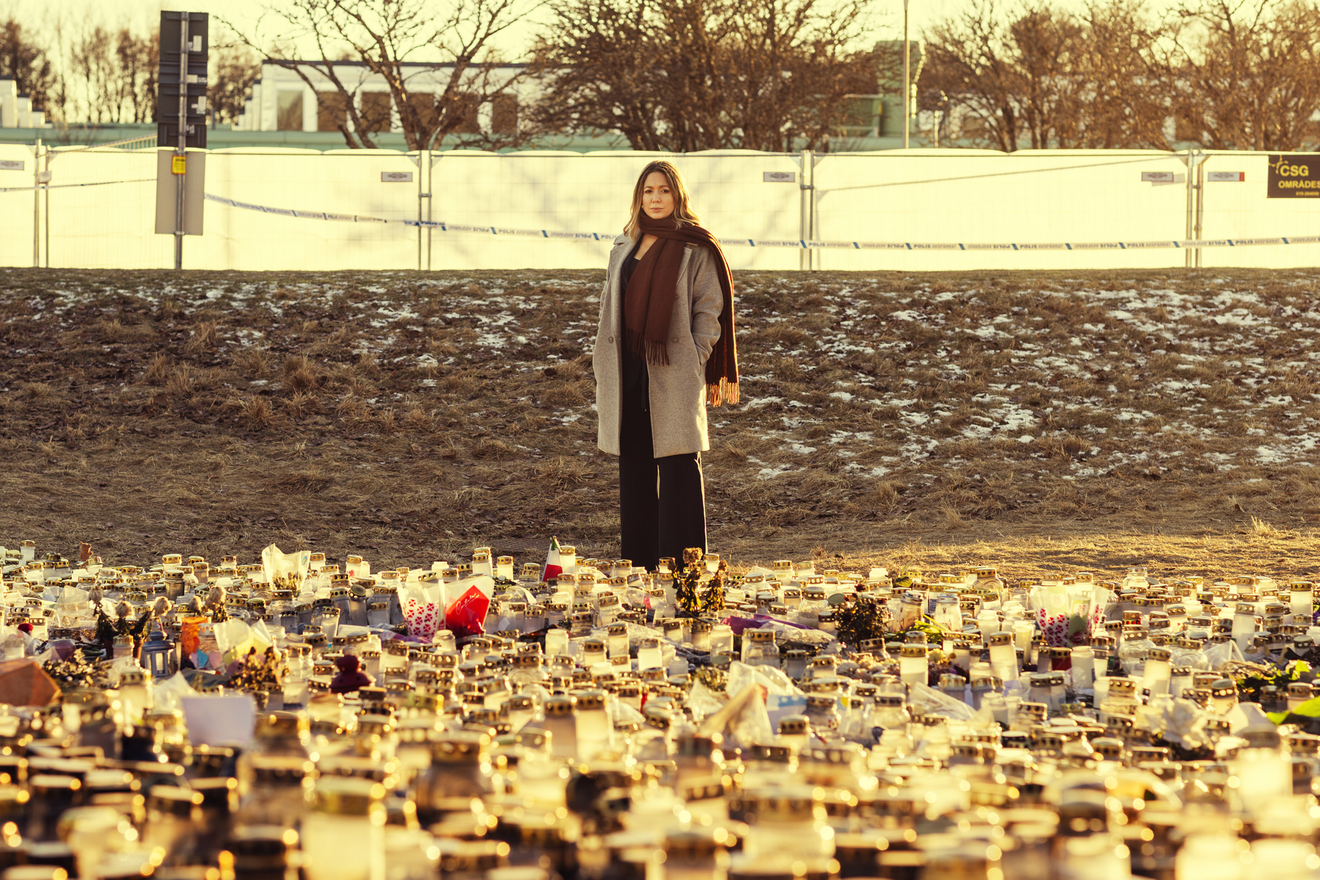Jennifer Mayer står framför ett hav av ljus utanför Risbergska skolan som är avspärrad med polisband och staket med insynsskydd.