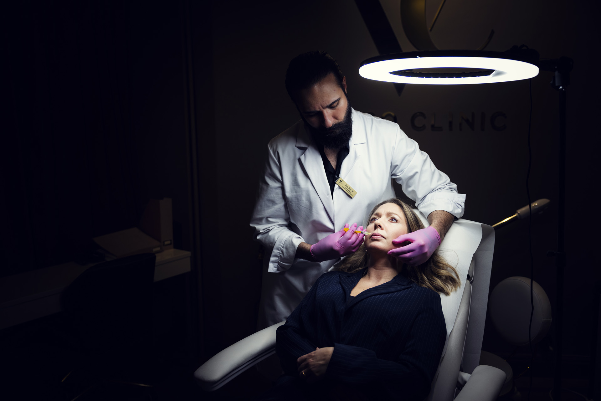 Läkaren Reza Shahraki håller en spruta med filles mot Jenifers Mayers läppar för att visa hur det går till när man injicerar fillers.